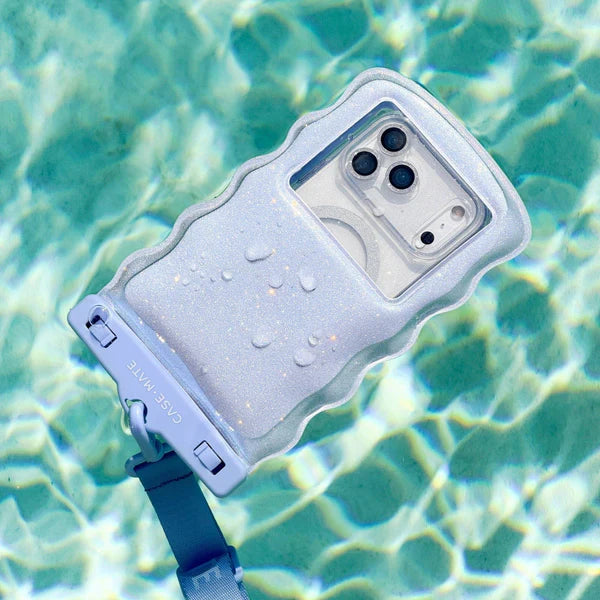 The Mist Twinkle Wavy Waterproof Floating Phone Pouch, in light purple, floats on the clear blue surface of a swimming pool with sunlight glinting off the water and droplets visible on its sturdy IP68 waterproof design.