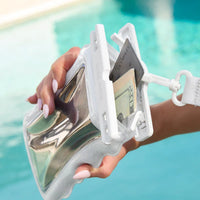 A hand holds the Ivory Twinkle Wavy Waterproof Floating Phone Pouch by a pool, with a credit card and cash partially visible from the pouch’s secure white latch.